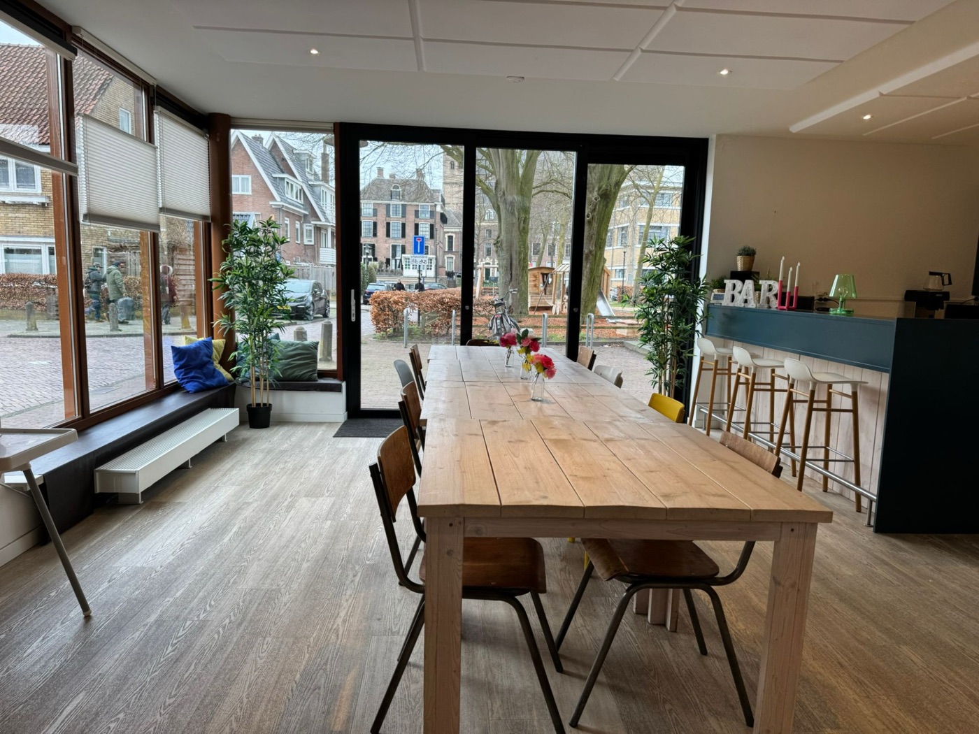 De grote zaal van het buurthuis met grote tafel en bar