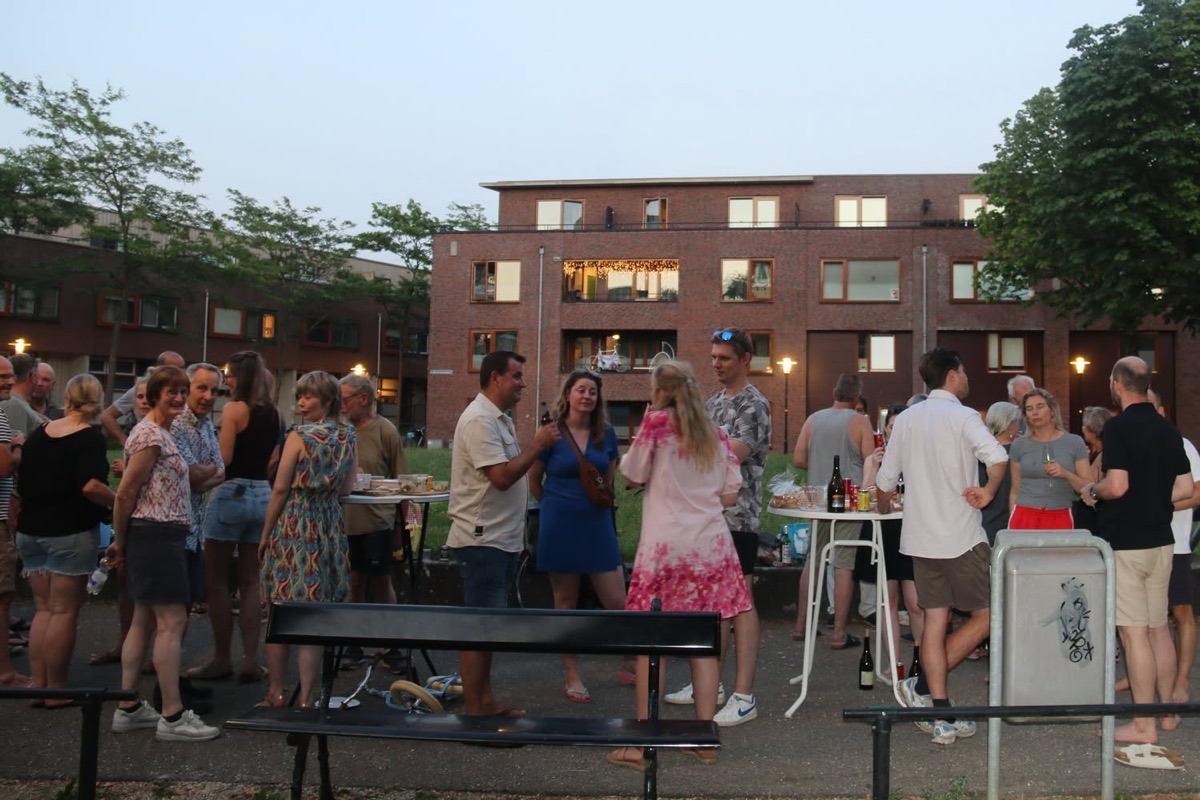 Buren staan in de avondzon te borrelen op het plein