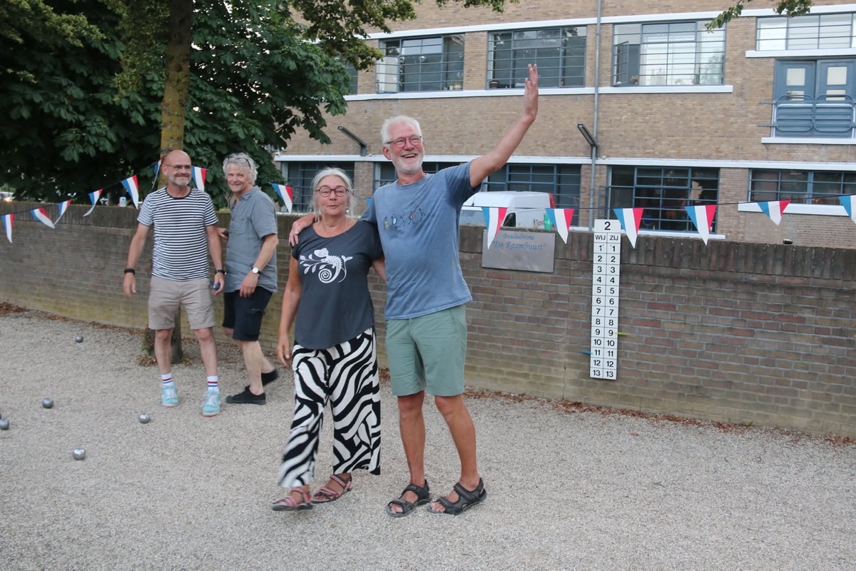Vier spelers poseren bij het scorebord langs de jeu-de-boulesbaan